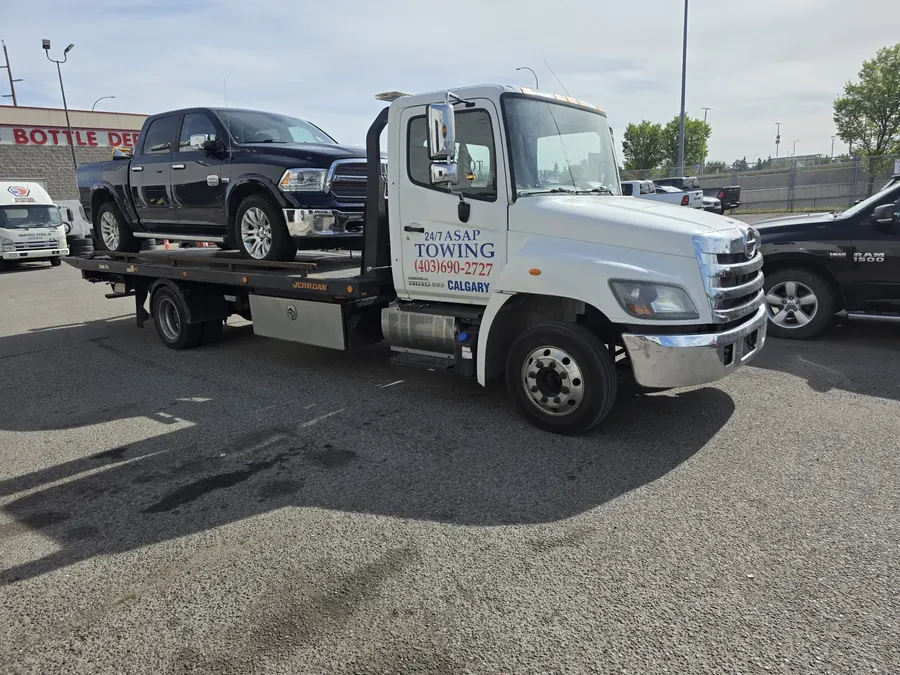 24/7 ASAP Towing flatbed truck with a pickup truck loaded in a Calgary lot